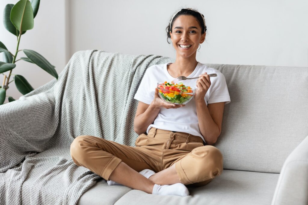 Good looking young woman eating vegetable salad